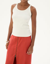 Modelo vestindo regata decote U de malha ribana off-white com saia vermelha.