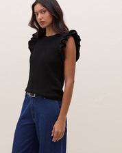 Modelo vestindo blusa de tricot preta com manga de babados, combinada com calça jeans.