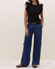 Modelo em pose lateral vestindo blusa de tricot preta com manga de babados.