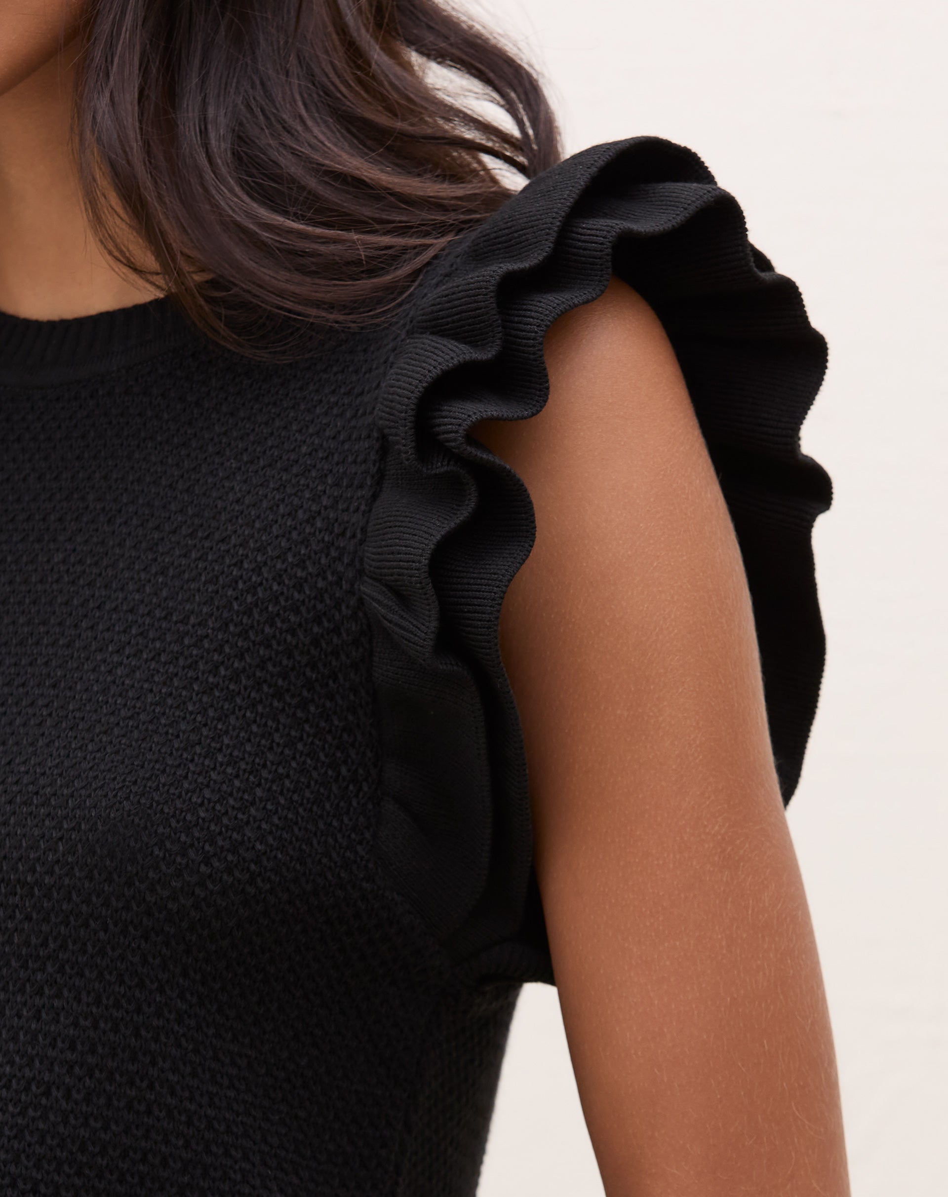 Blusa de tricot preta com manga de babados, vista de perto mostrando detalhes do tecido.