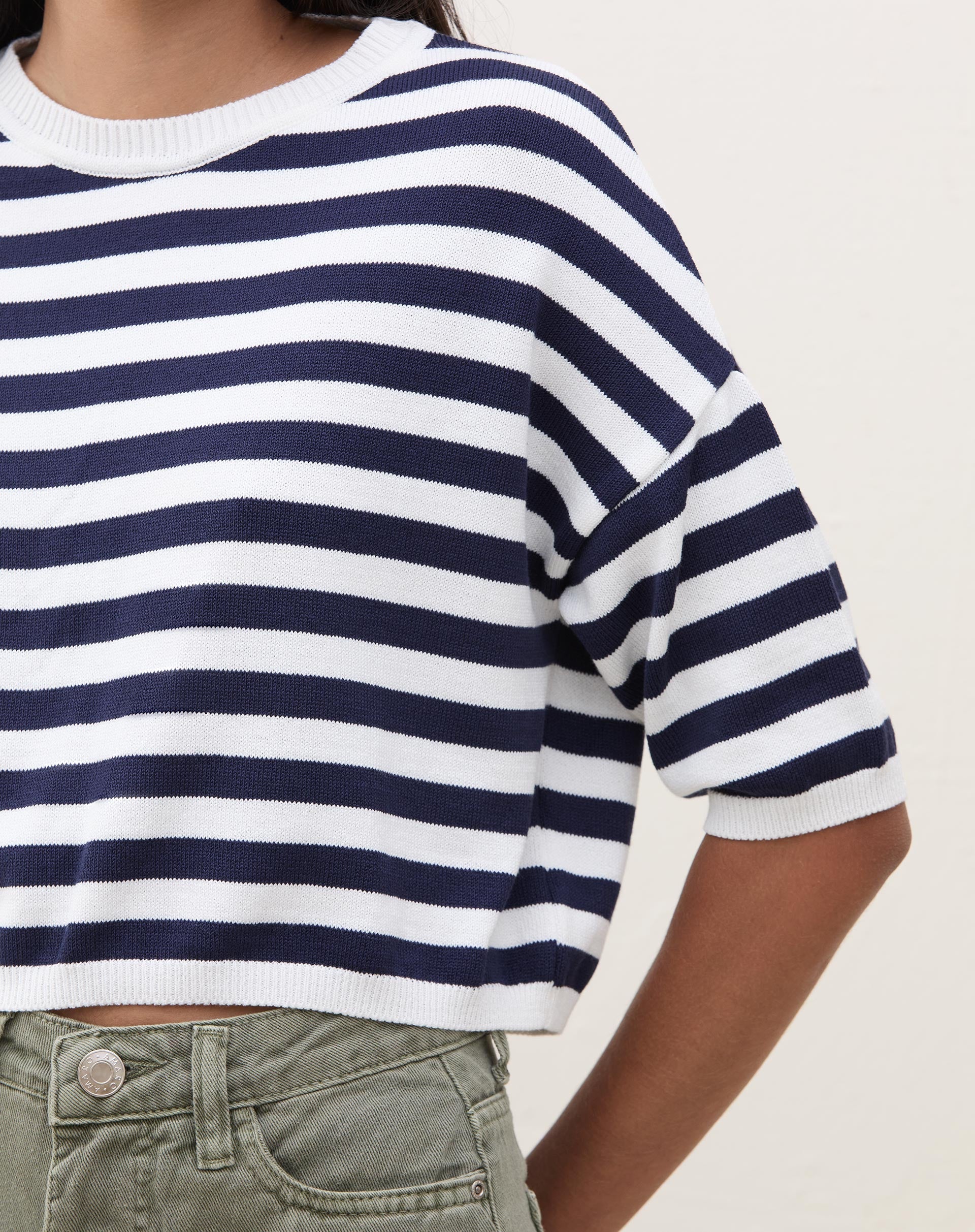 Vista traseira da camiseta cropped de tricot listrada azul marinho e branco.