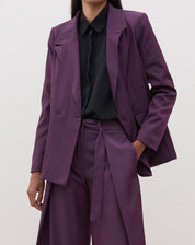 Blazer roxo com transpasse em alfaiataria, visto de frente.