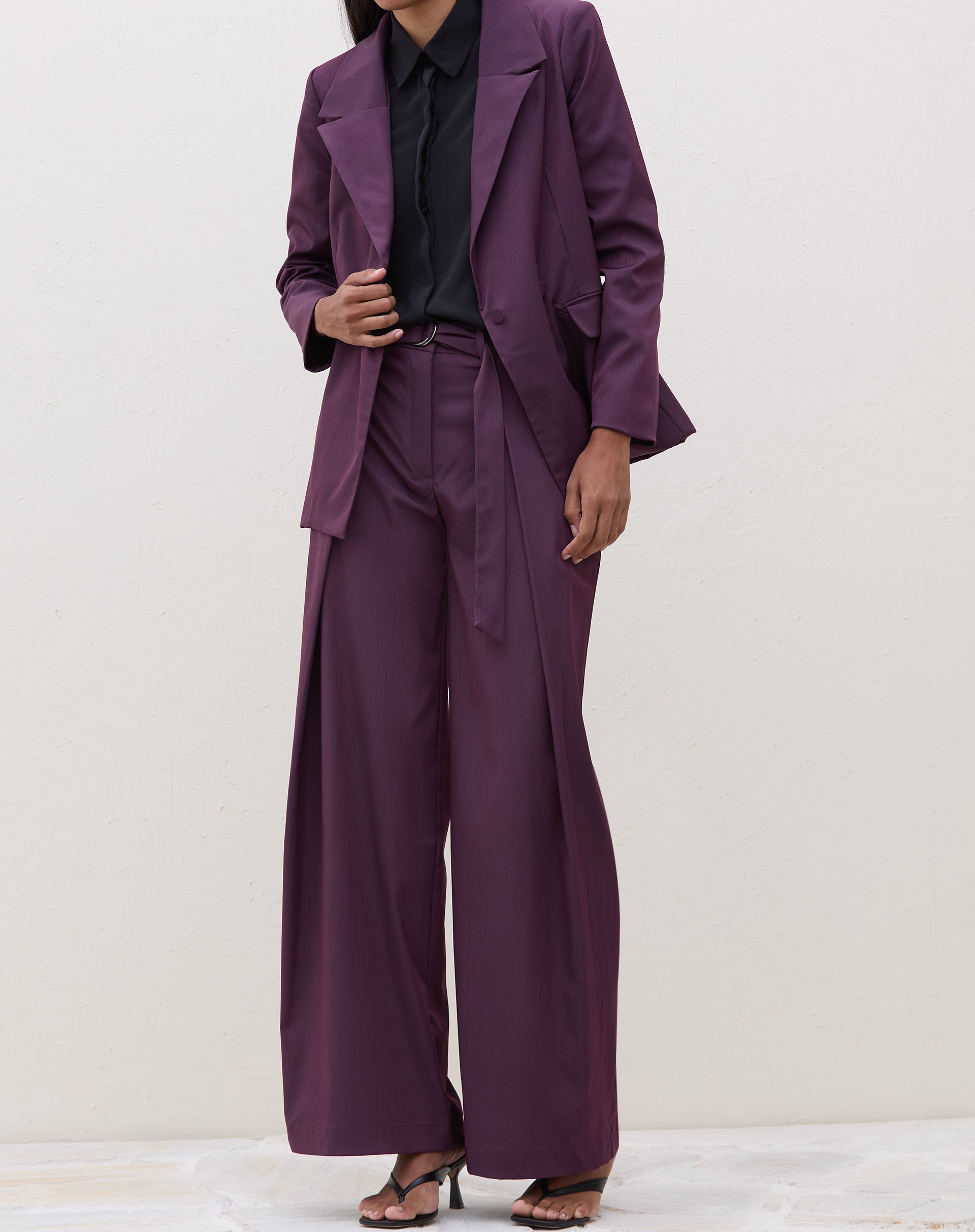 Conjunto de blazer roxo e calça de alfaiataria, visto de corpo inteiro.