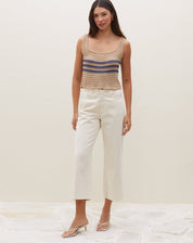 Modelo vestindo calça sarja wide cropped off-white com top de crochê listrado, vista lateral.