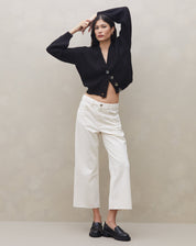 Modelo vestindo calça sarja wide cropped off-white com cardigan preto, vista frontal.