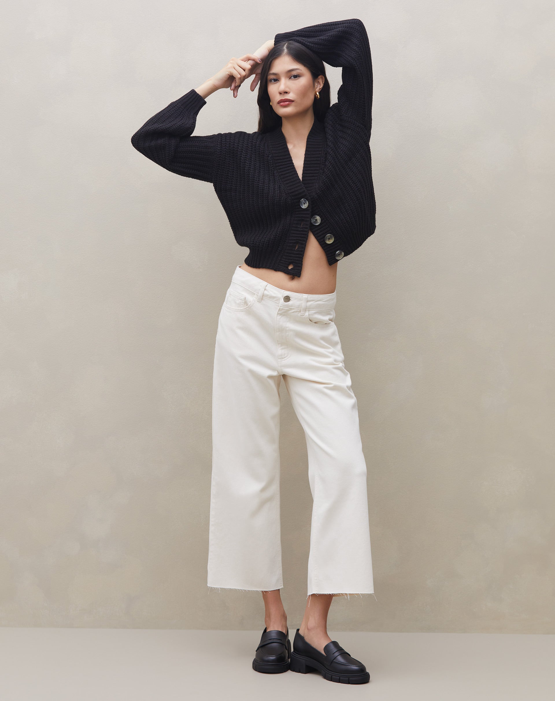 Modelo vestindo calça sarja wide cropped off-white com cardigan preto, vista frontal.
