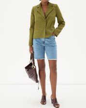 Modelo vestindo blazer verde militar com shorts jeans e bolsa.