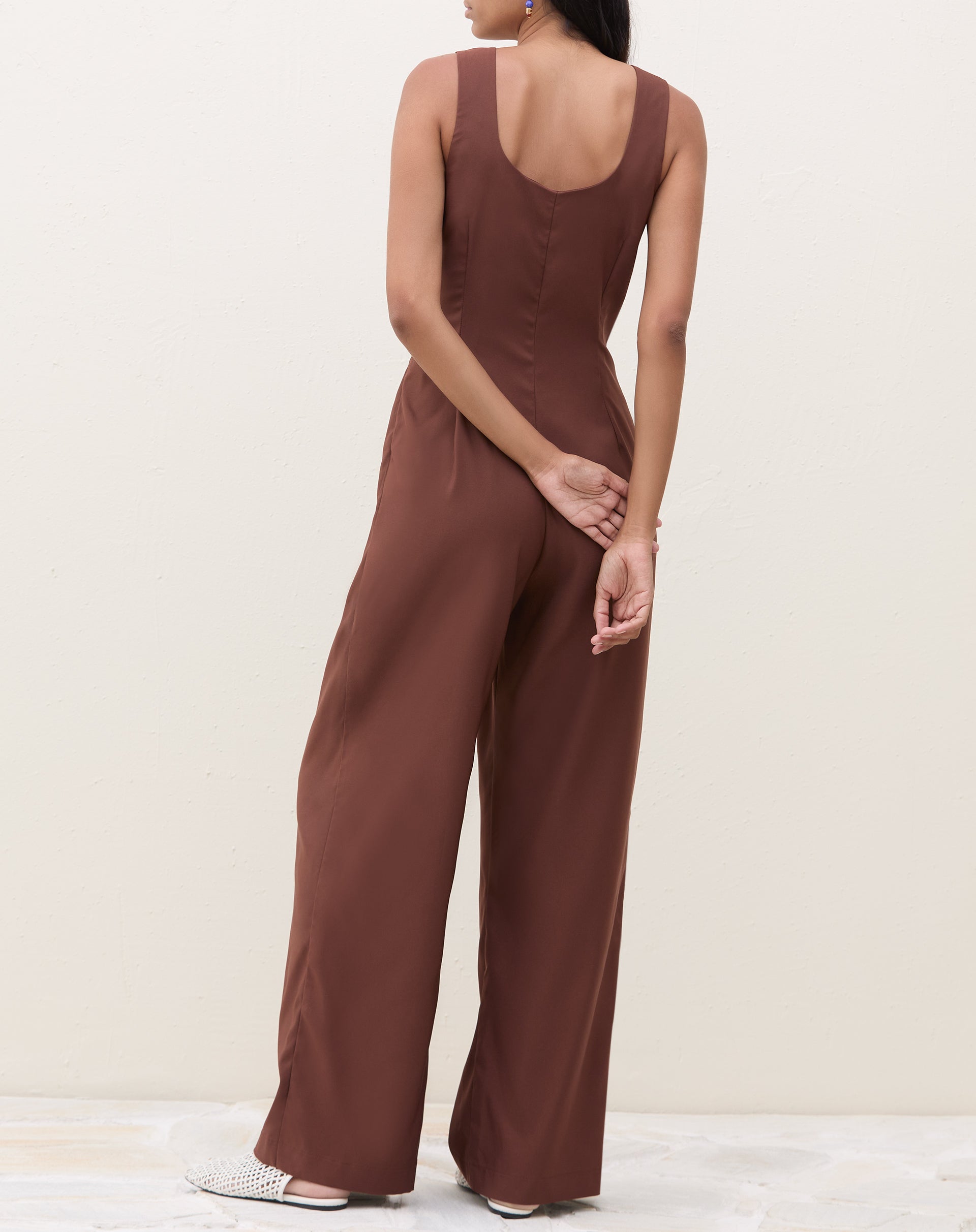 Imagem de um macacão marrom com pregas, visto de costas.