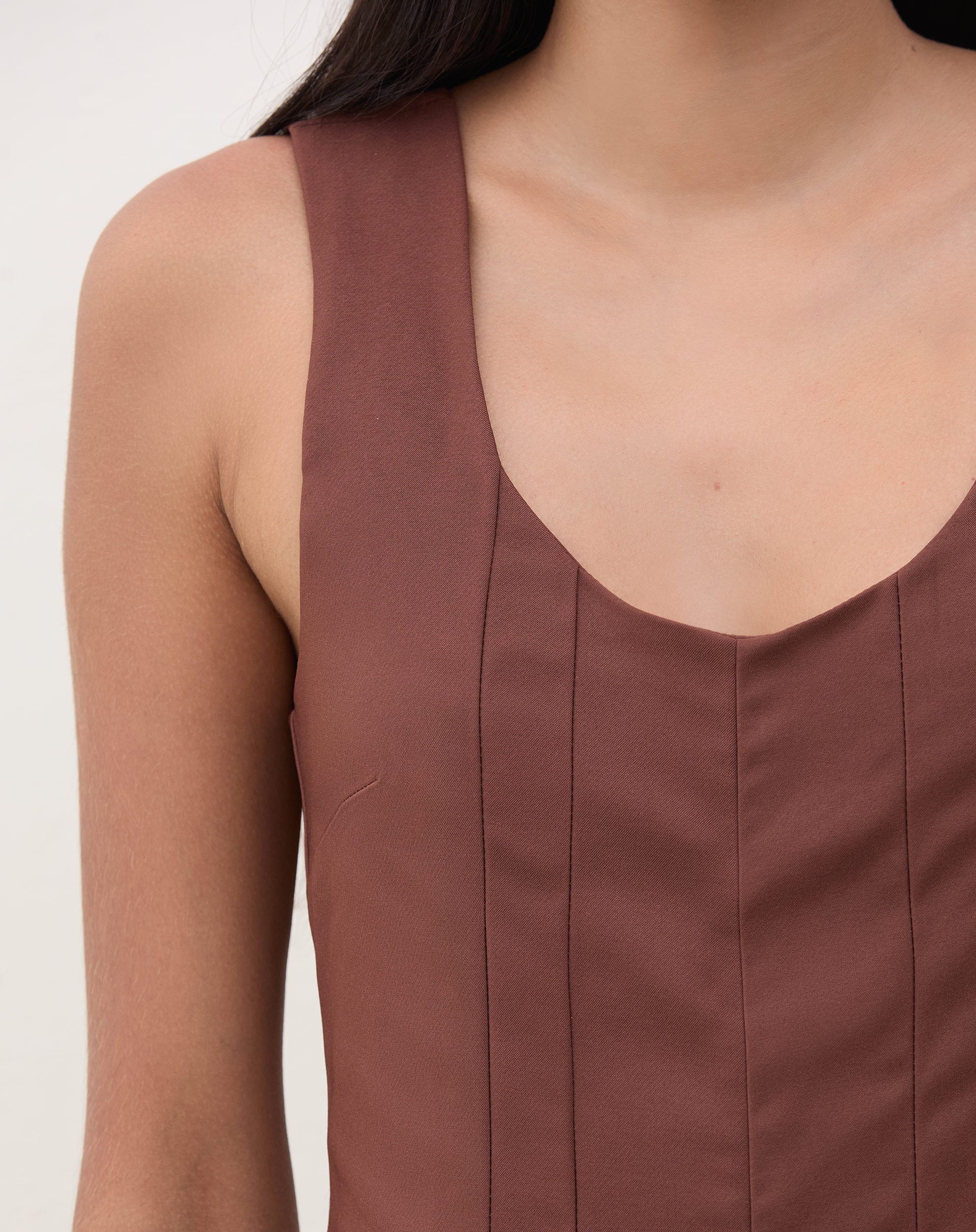 Imagem de um macacão marrom com pregas, mostrando detalhes da cintura.