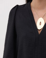 Detalhe do decote V da blusa preta.