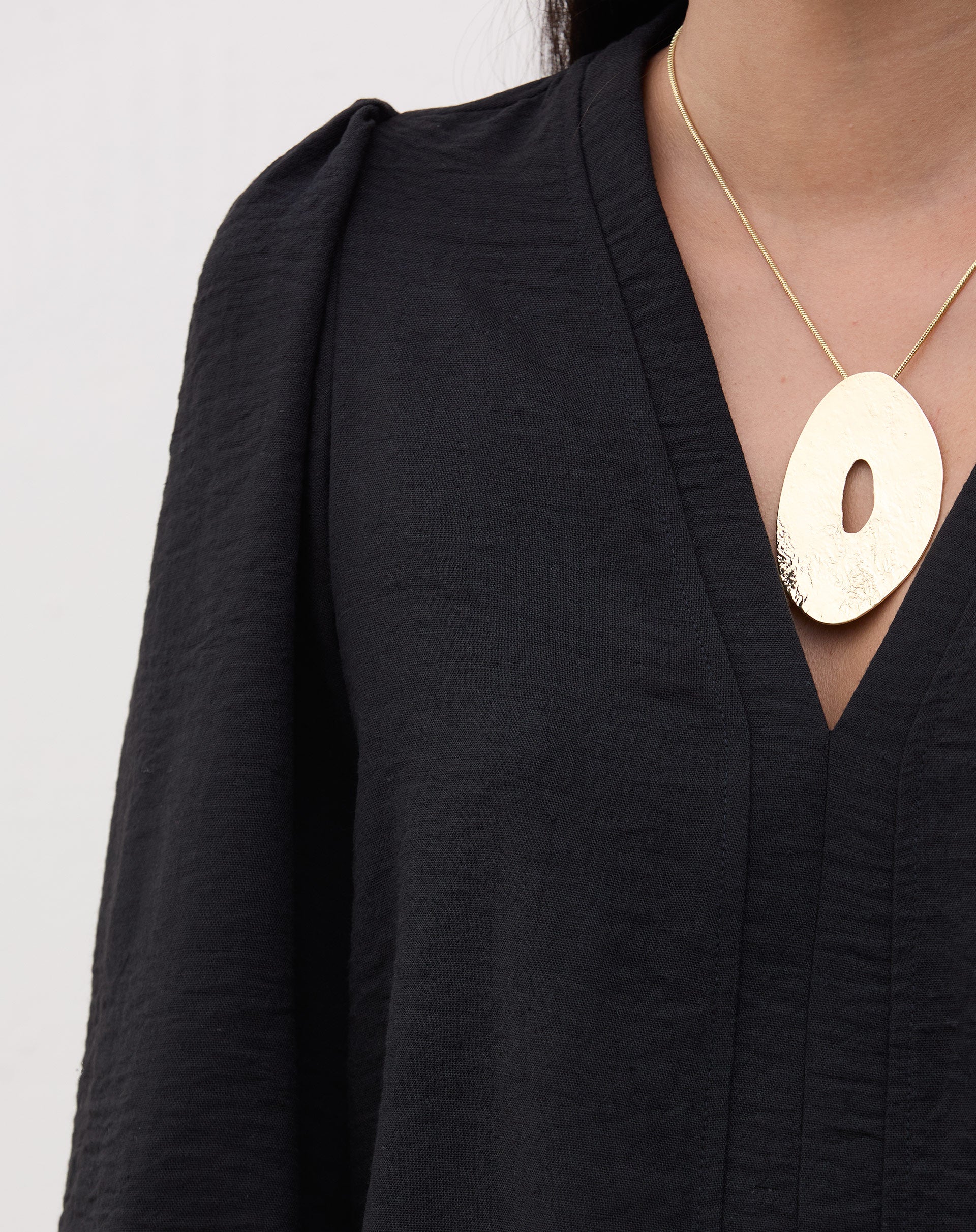 Detalhe do decote V da blusa preta.