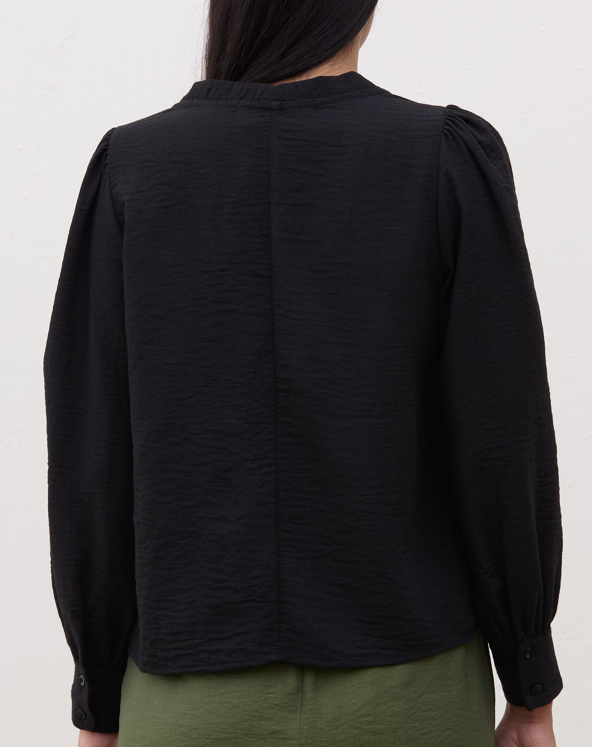 Vista traseira da blusa preta com manga longa.