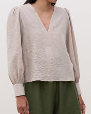 Blusa manga longa bege com decote V, vista frontal.