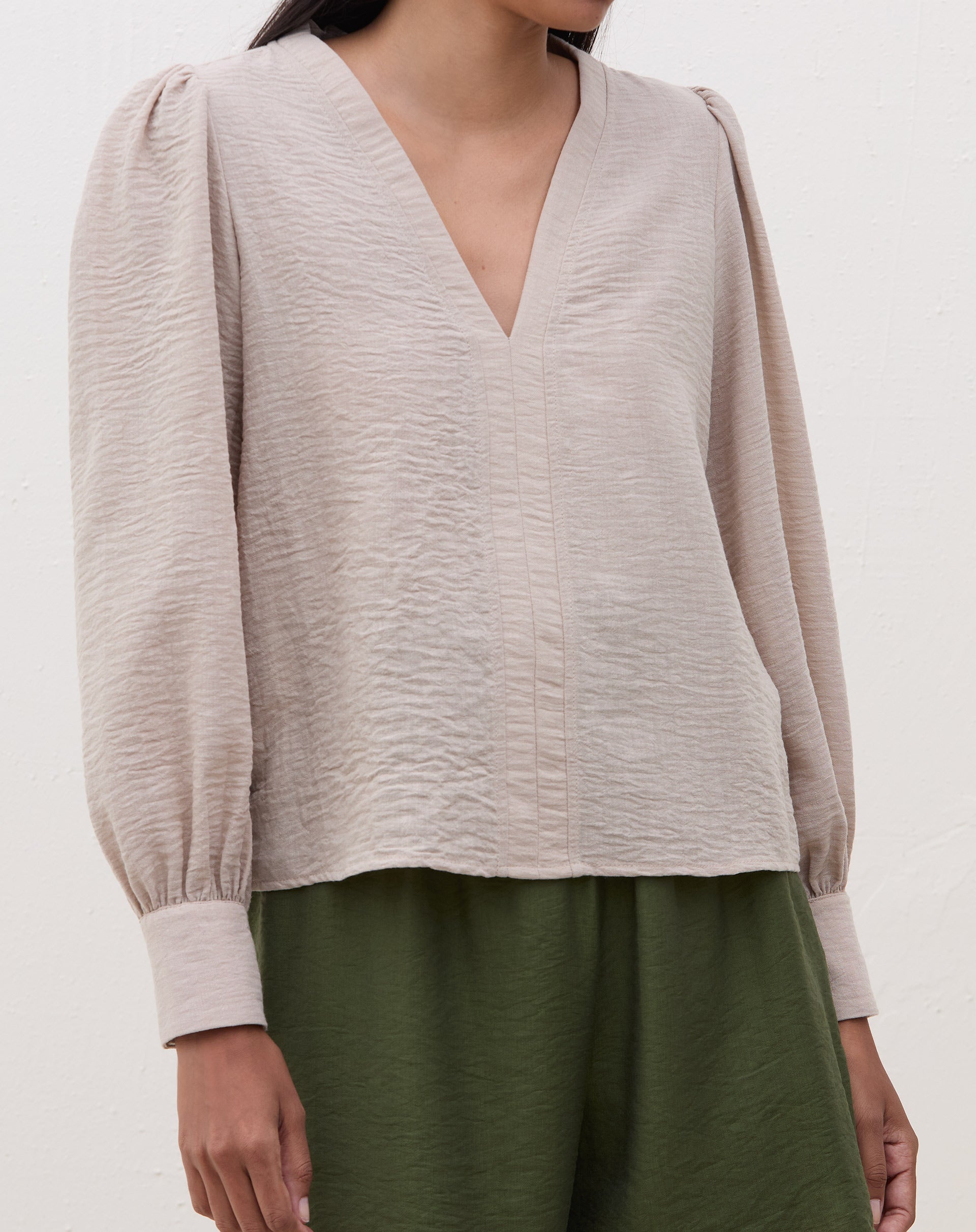 Blusa manga longa bege com decote V, vista frontal.