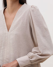 Vista traseira da blusa bege com mangas longas.