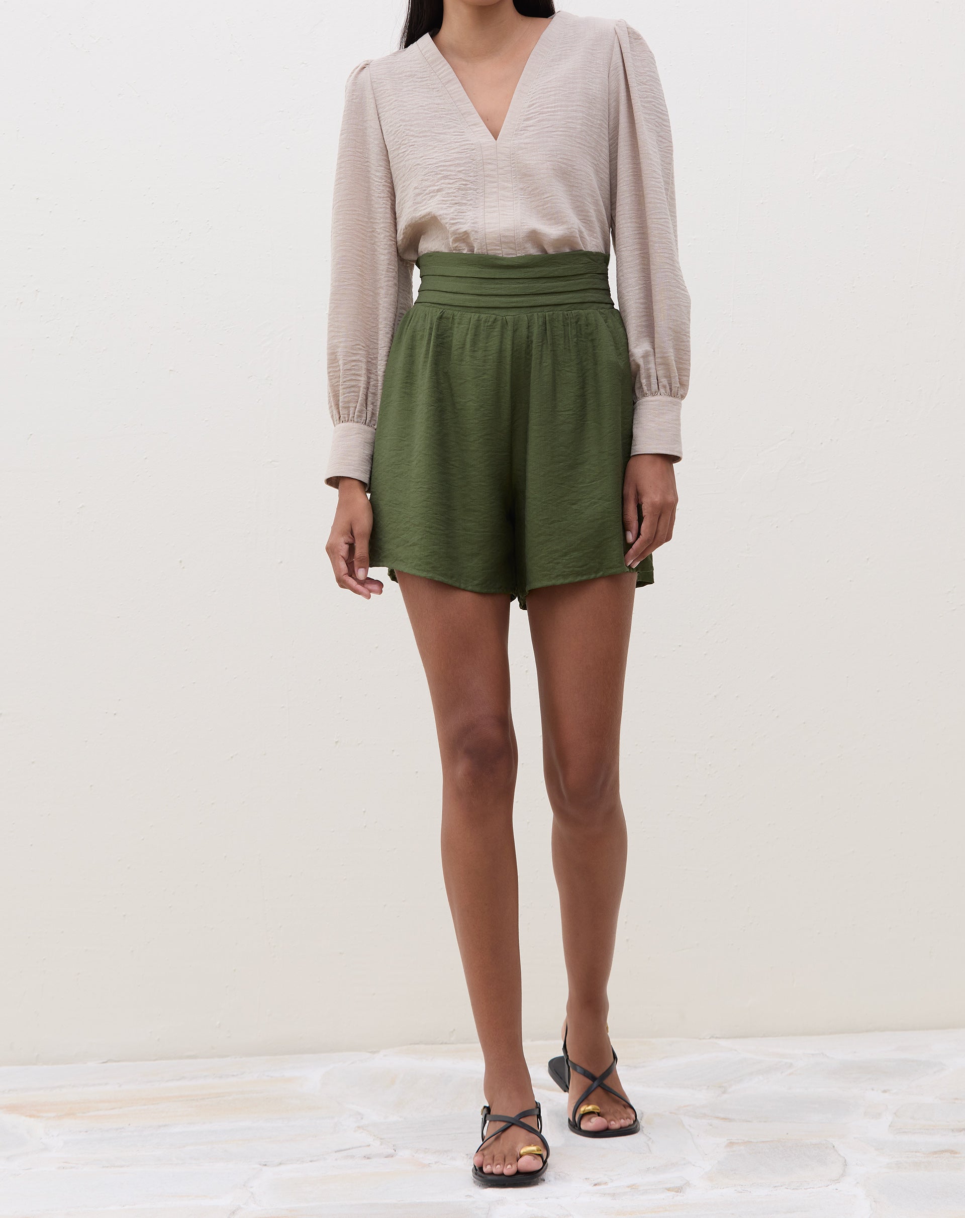 Modelo vestindo a blusa bege com shorts verdes.