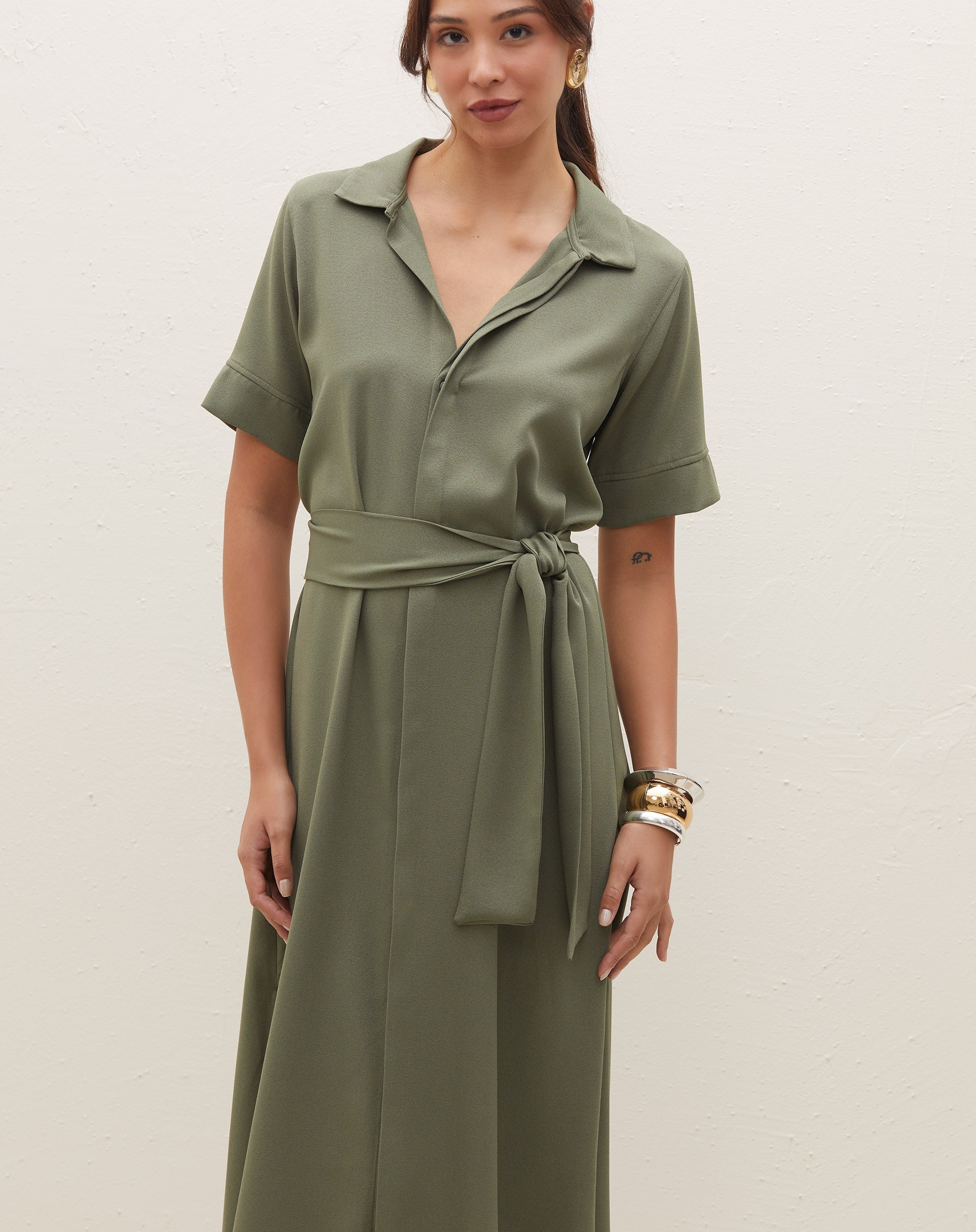 Detalhe da chemise midi verde militar com cinto de amarração, mostrando o design da gola polo.