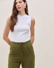 Modelo vestindo calça reta verde militar com blusa branca sem mangas, vista frontal.