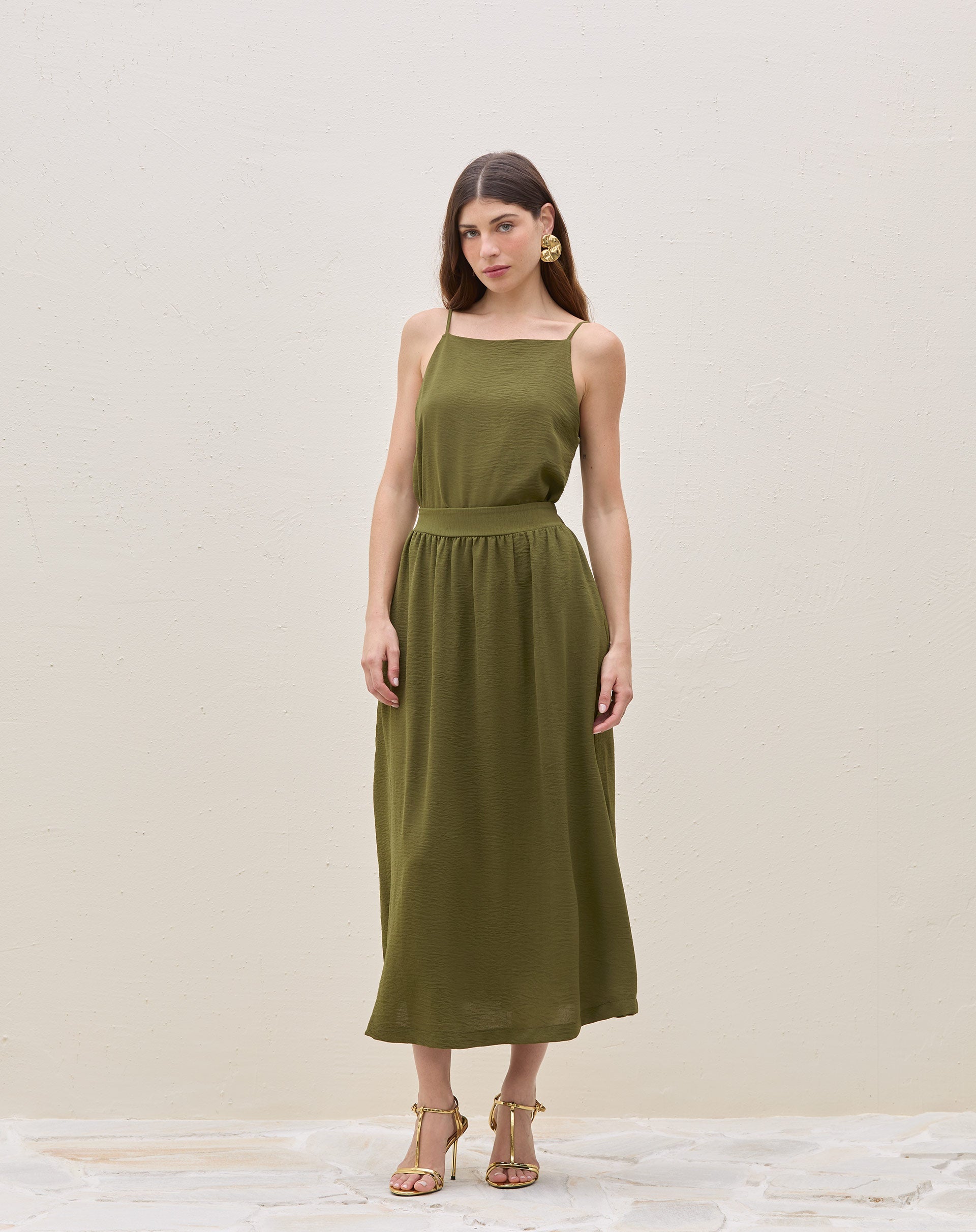 Modelo vestindo saia midi franzida verde militar com blusa sem mangas, vista frontal.