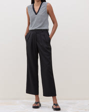 Modelo vestindo calça reta preta com cós transpassado, vista frontal.