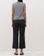 Modelo vestindo calça reta preta com cós transpassado, vista traseira.