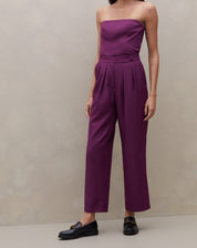 Modelo vestindo calça reta roxa com cós transpassado, vista frontal completa.