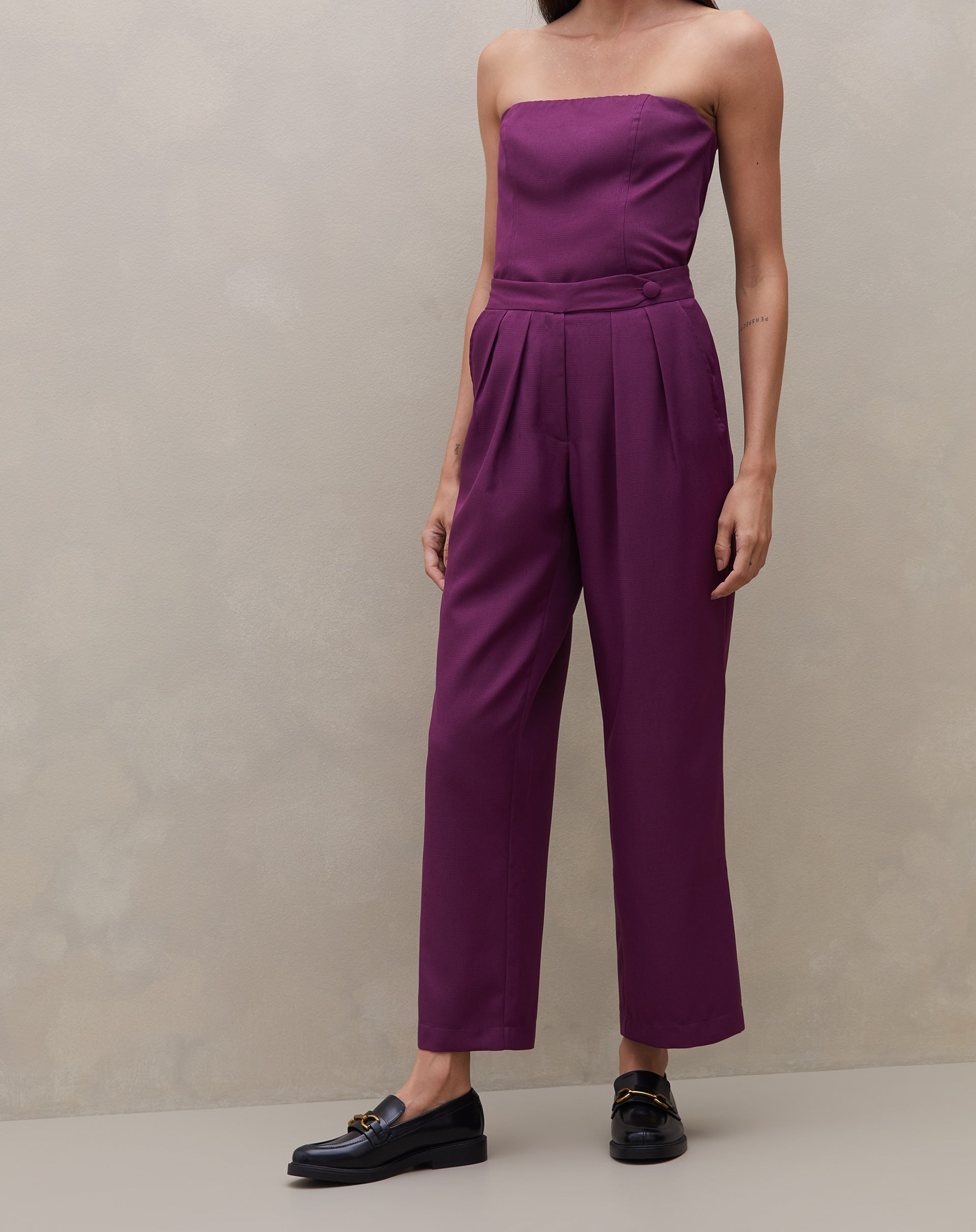 Modelo vestindo calça reta roxa com cós transpassado, vista frontal completa.