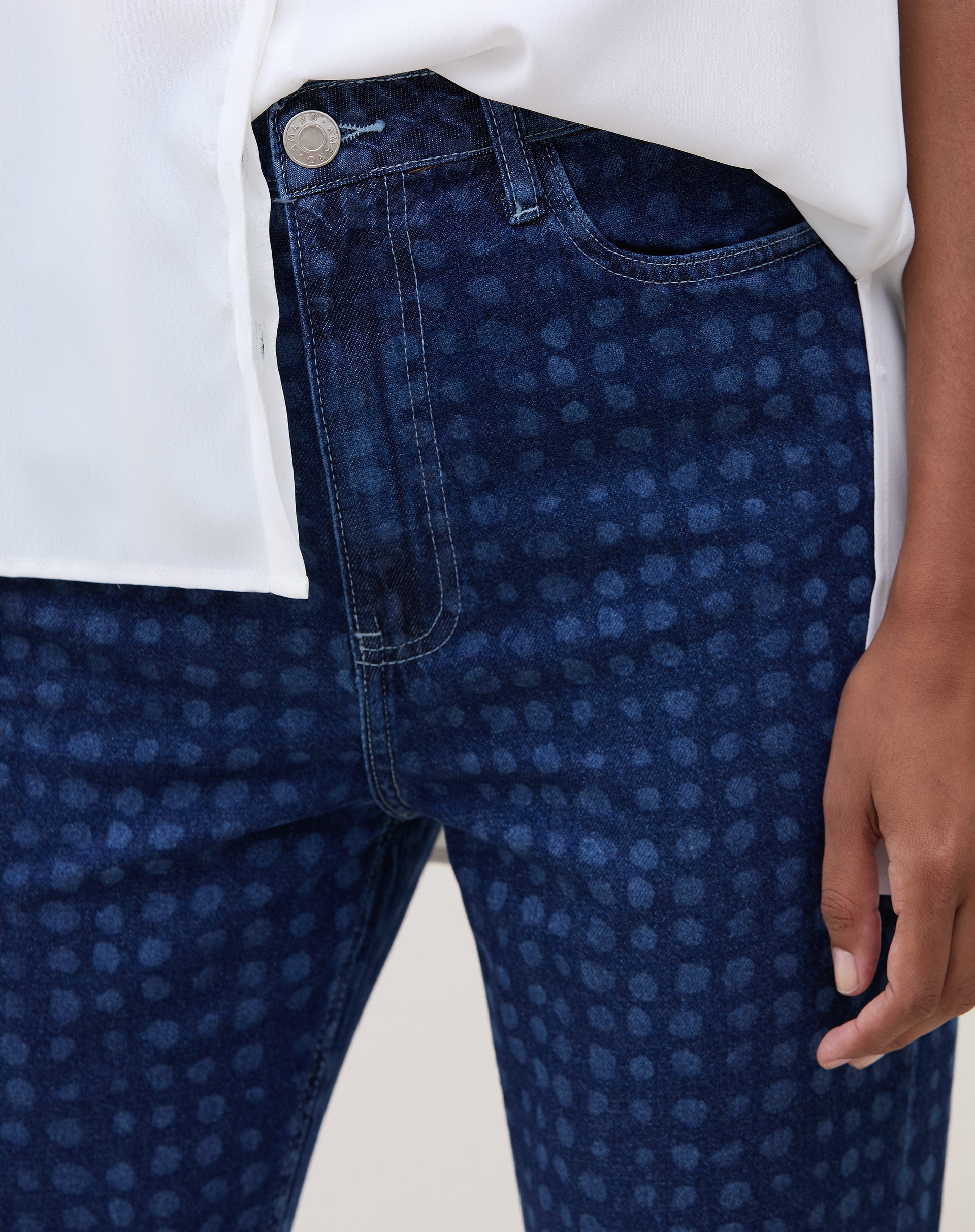 Detalhe do cós alto e fechamento com botão da calça Mom Jeans azul médio.