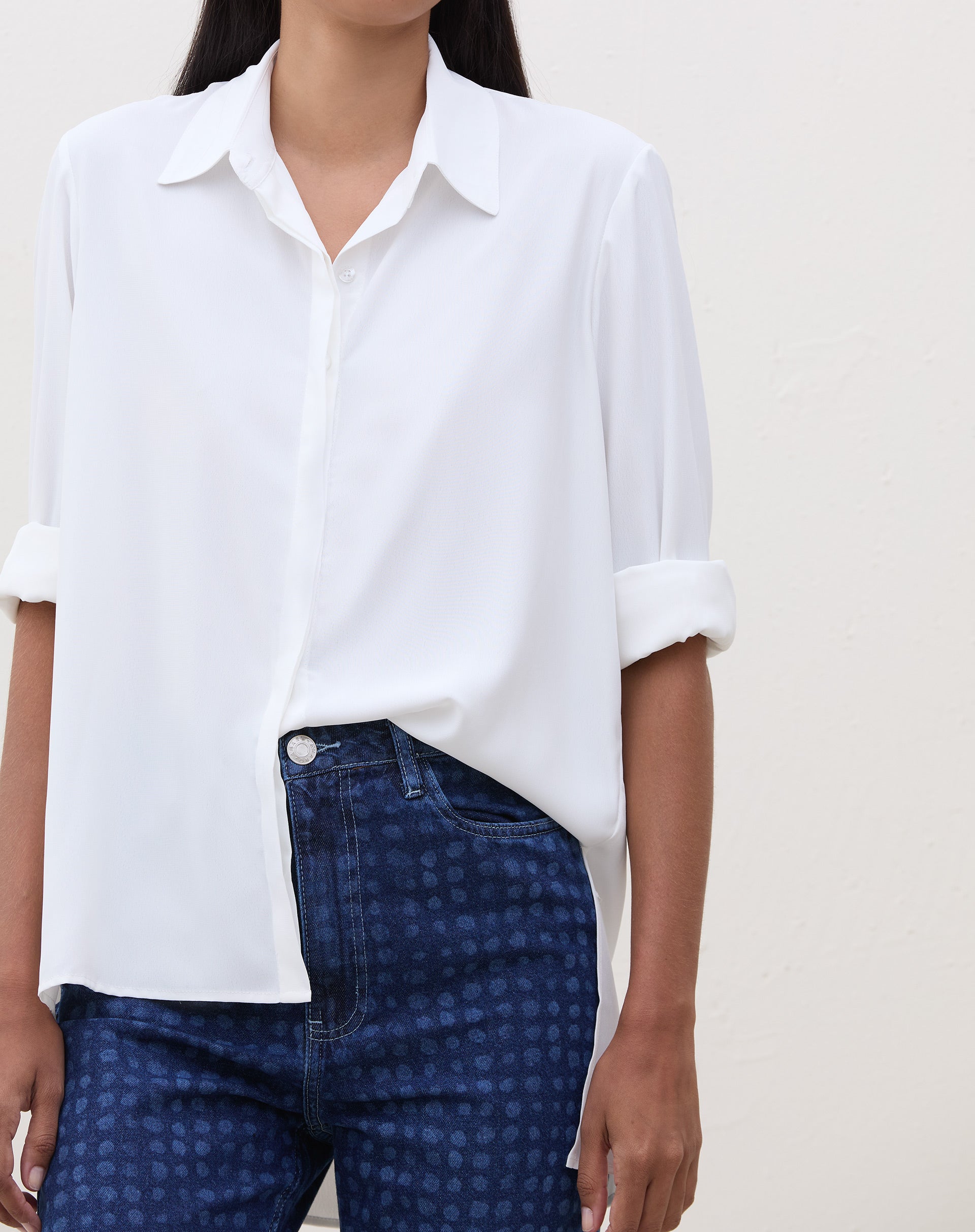 Close-up da camisa branca combinada com a calça Mom Jeans azul médio.