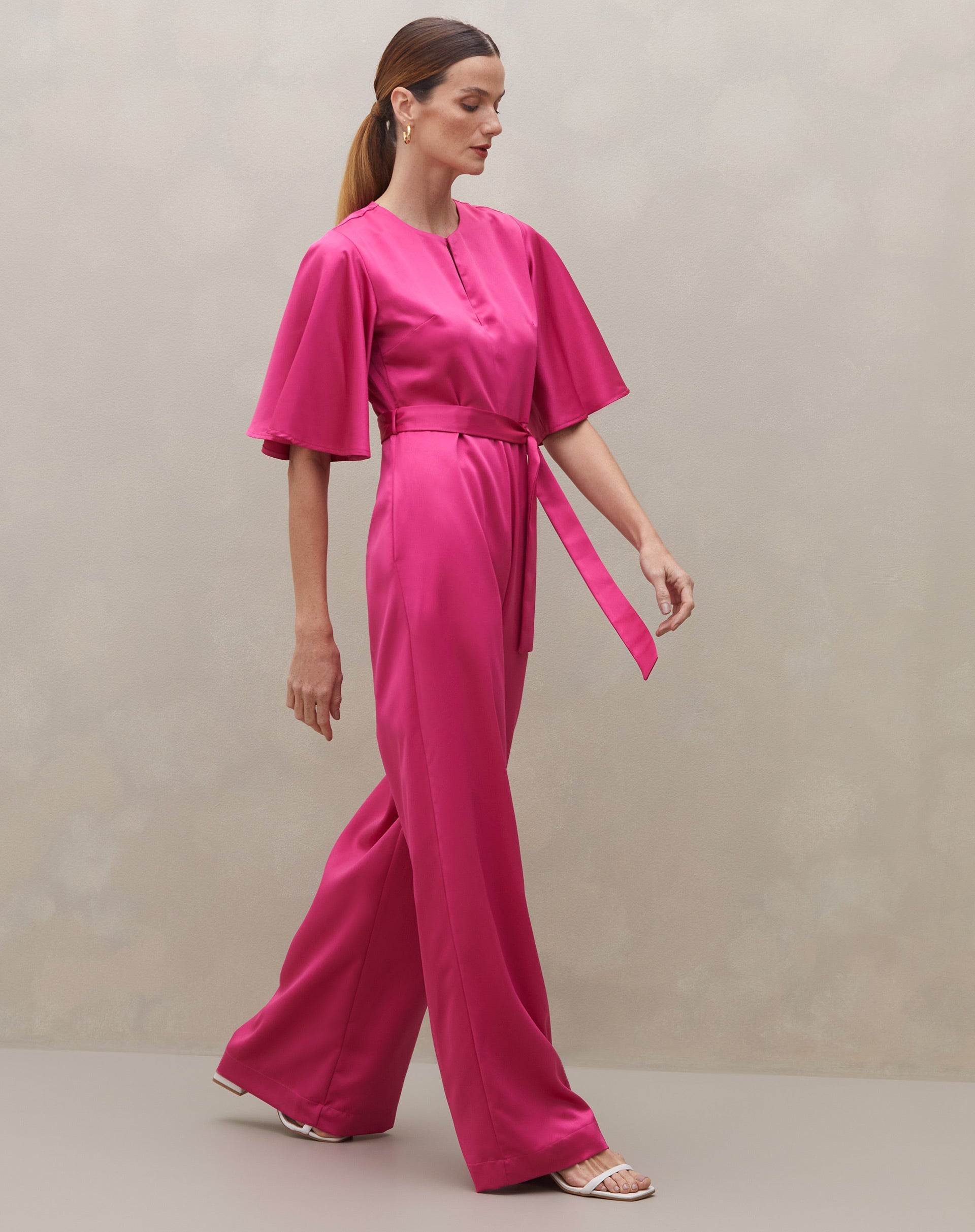 Macacão rosa escuro com mangas sino e cinto, vista lateral.