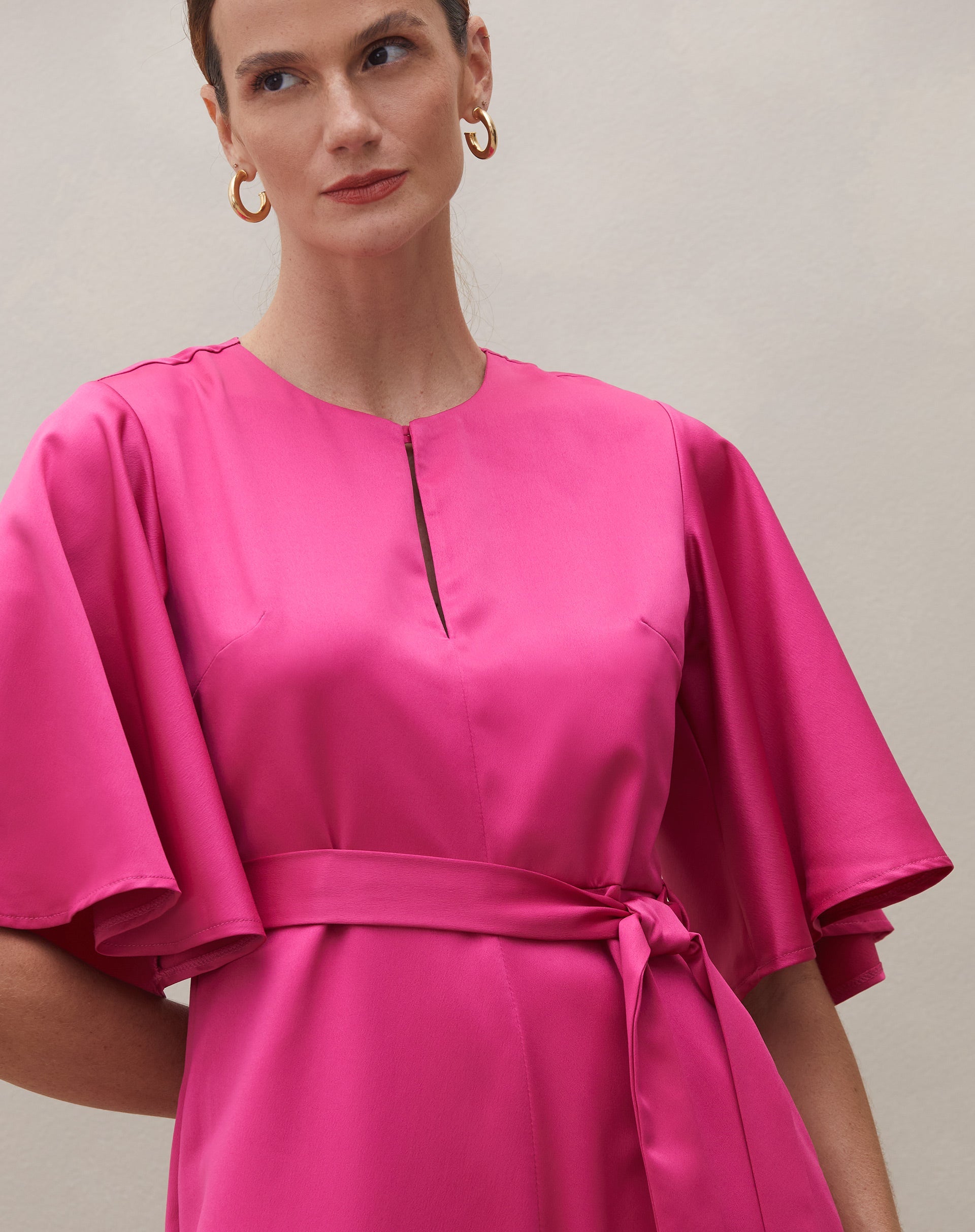 Detalhe do decote redondo do macacão rosa escuro.