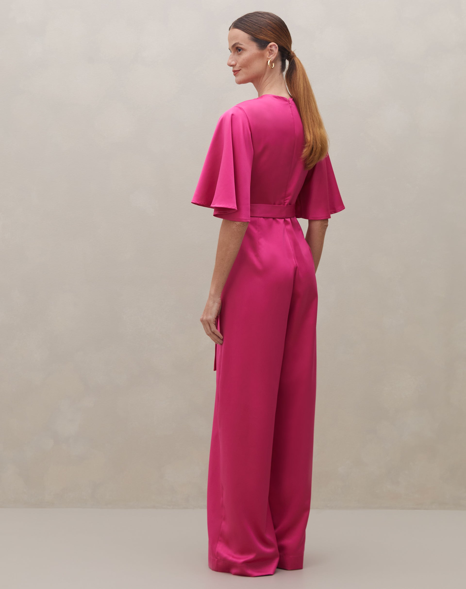 Macacão rosa escuro com mangas sino e cinto, vista traseira.