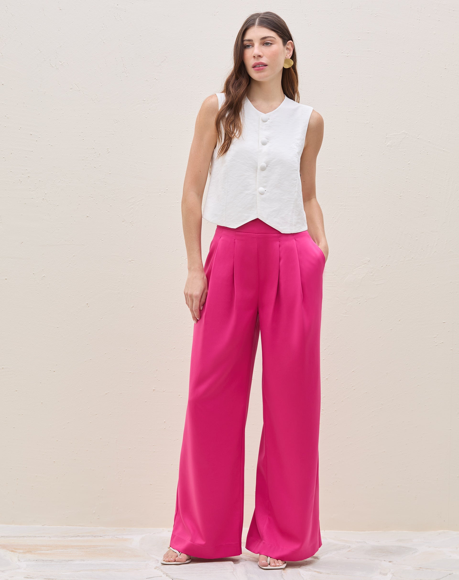 Modelo vestindo calça wide leg rosa escuro com pregas e top branco sem mangas.