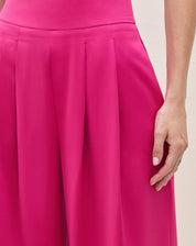 Detalhe do cós alto e pregas da calça wide leg rosa escuro.