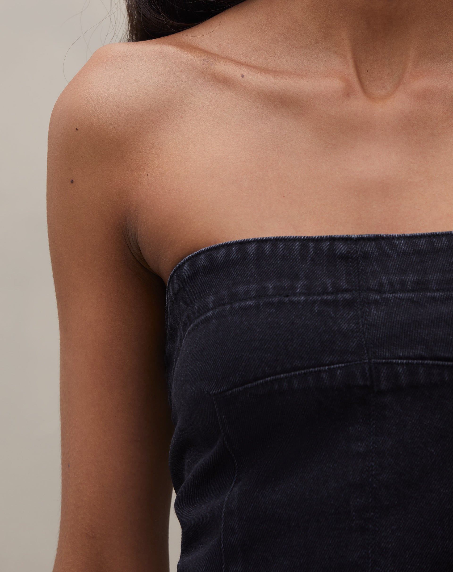 Detalhe do tecido jeans preto do top sem alça, destacando sua textura.