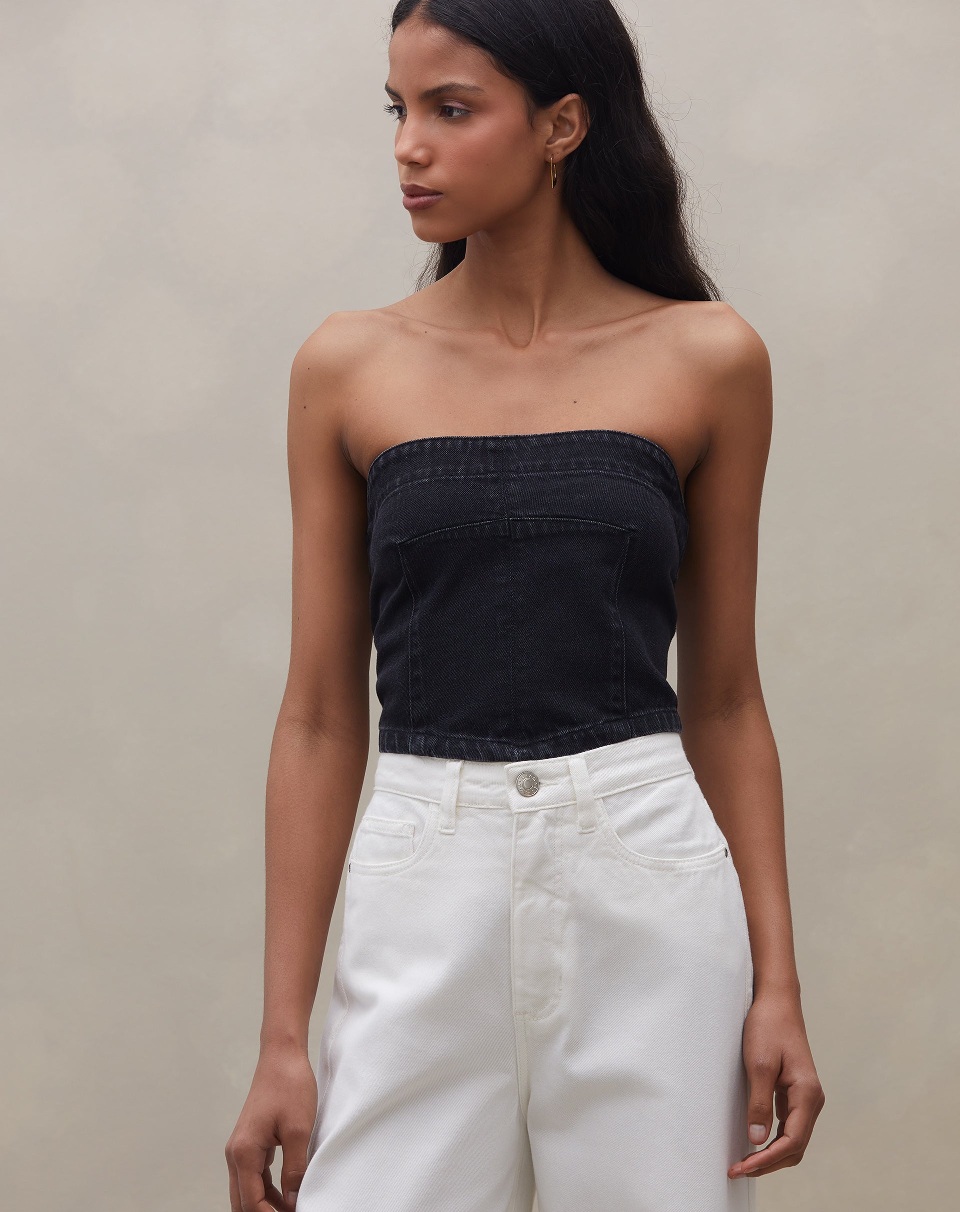 Modelo usando o top sem alça jeans preto em uma pose casual.