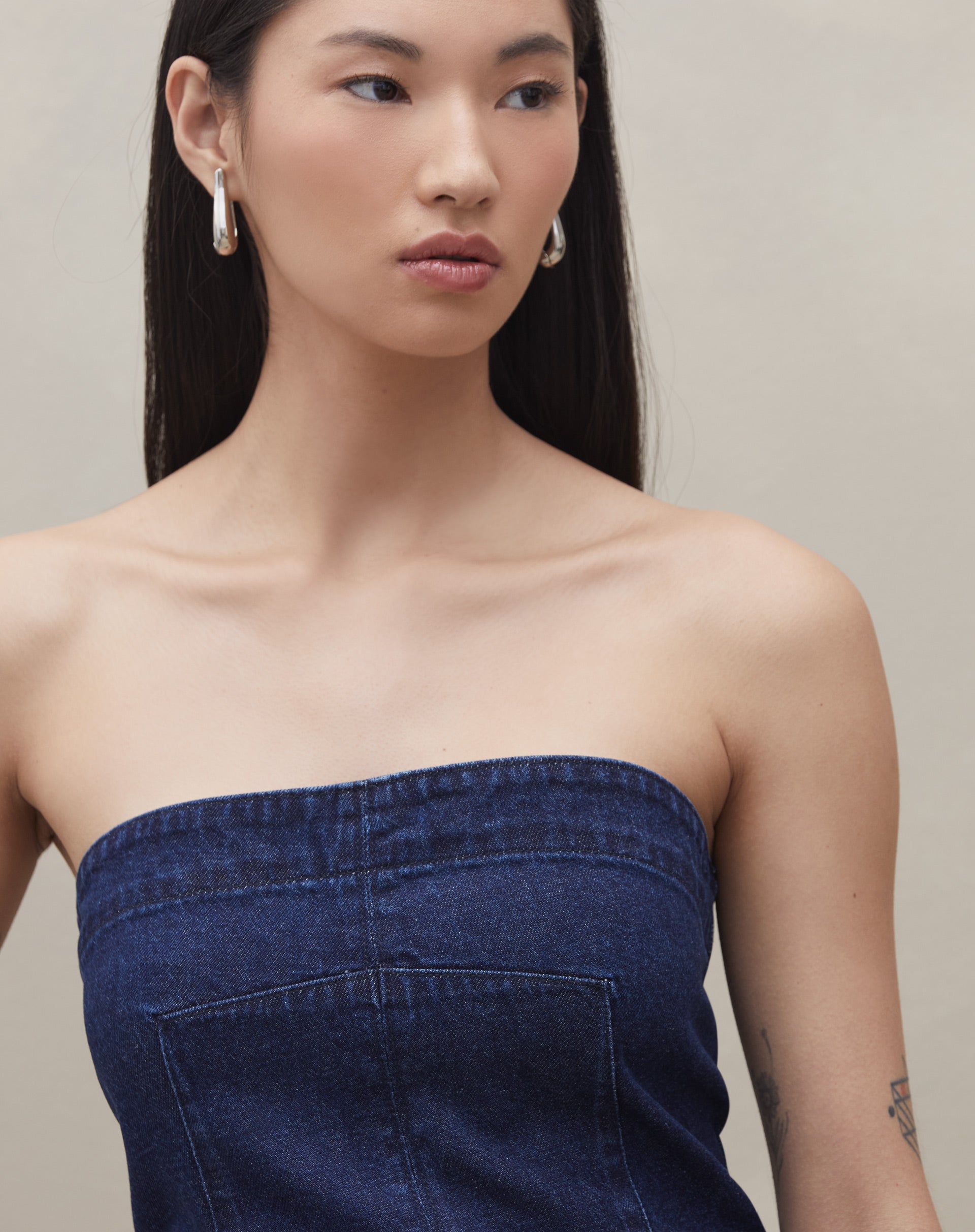 Detalhe do top sem alça jeans azul escuro, mostrando o tecido e acabamento.