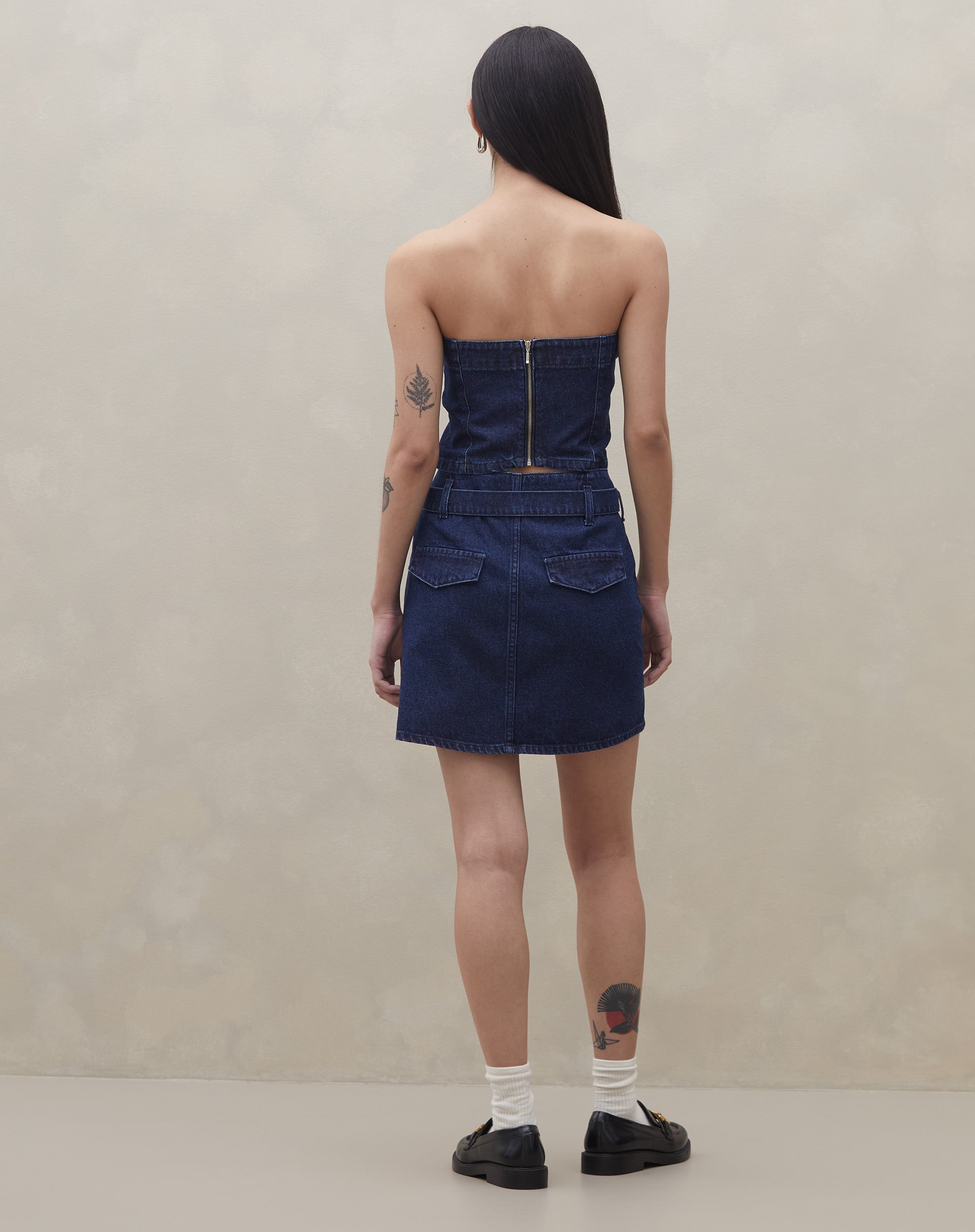 Vista traseira do top sem alça jeans azul escuro, com zíper visível.