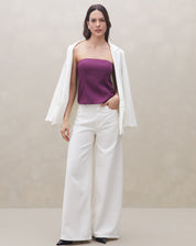 Modelo usando a blusa sem alça roxa com calça branca e blazer, criando um look sofisticado.