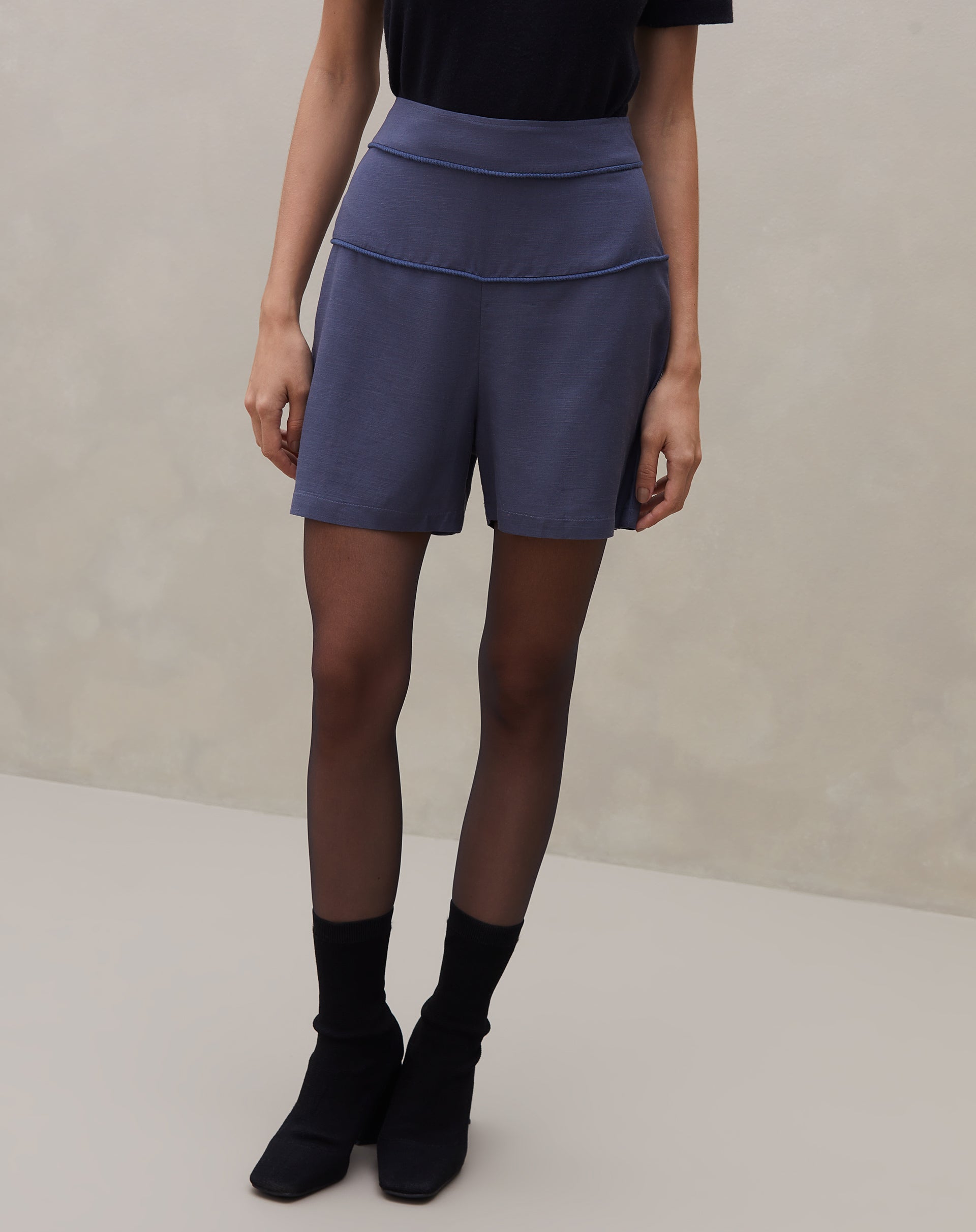 Close-up do shorts azul com detalhe de vivo contrastante na cintura.