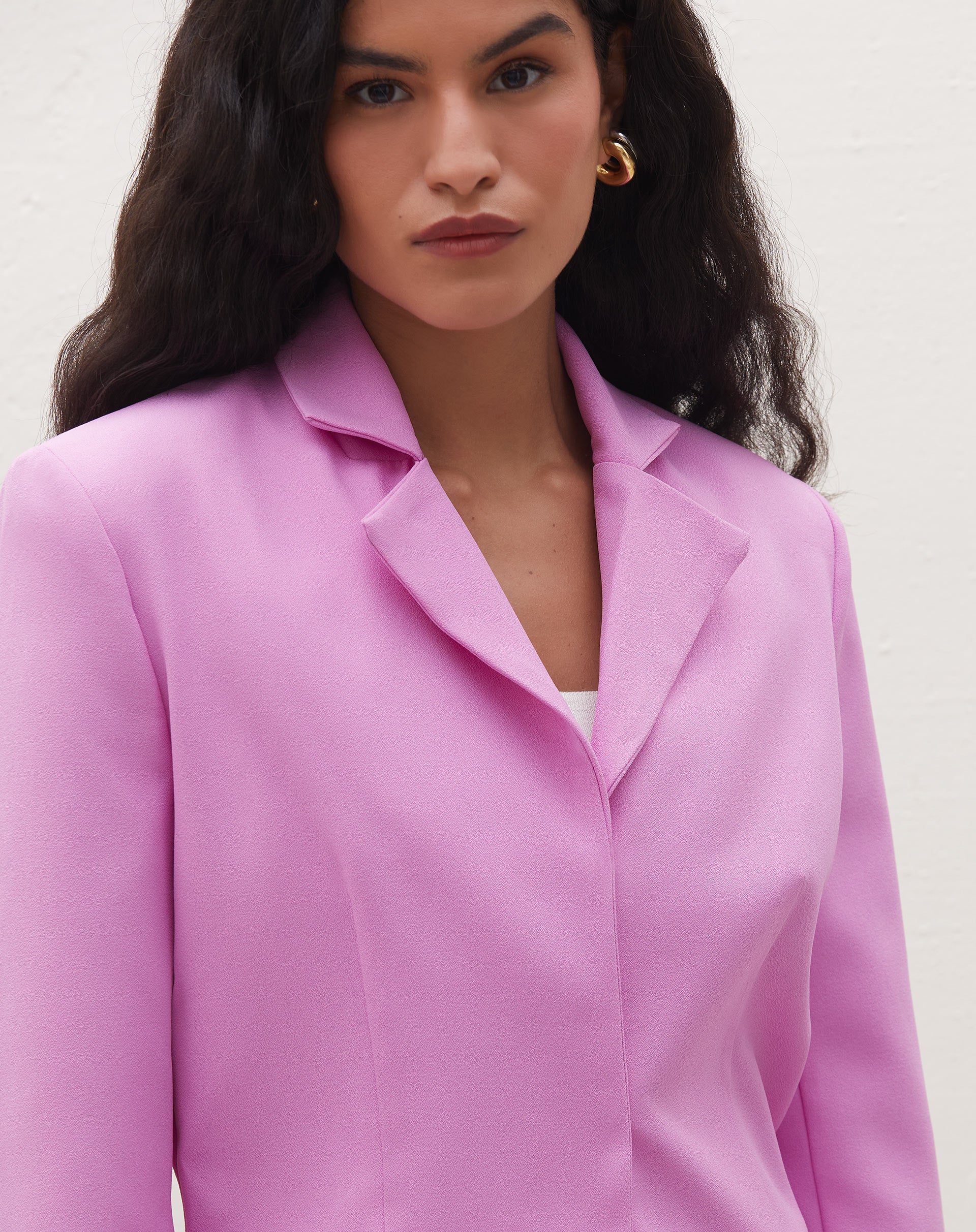 Vista lateral do blazer cropped rosa, destacando o comprimento e o ajuste.