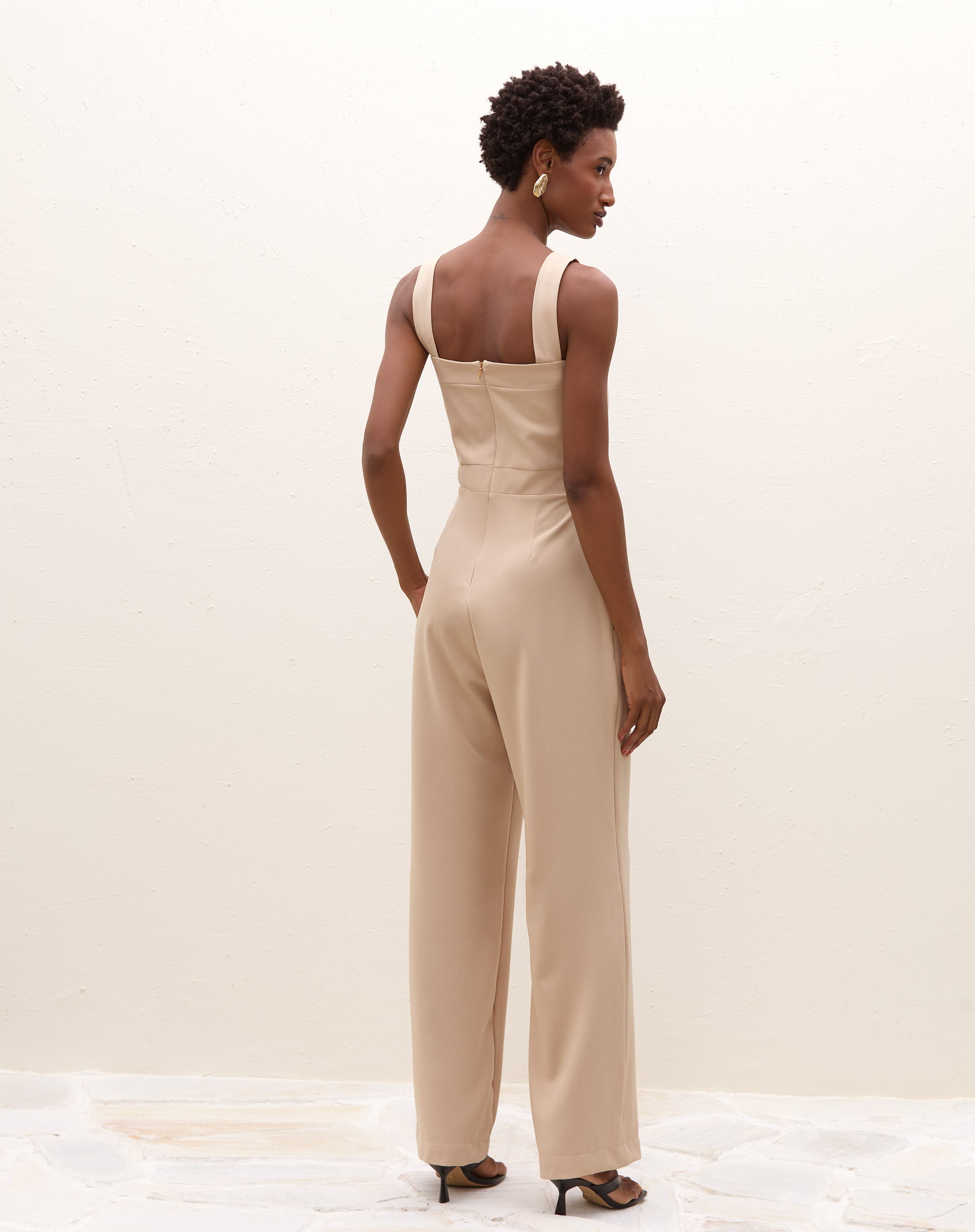 Detalhe da cintura ajustada e pernas retas do macacão.