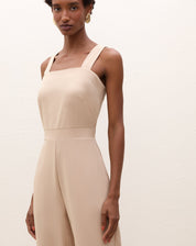 Vista lateral do macacão bege mostrando o caimento elegante.