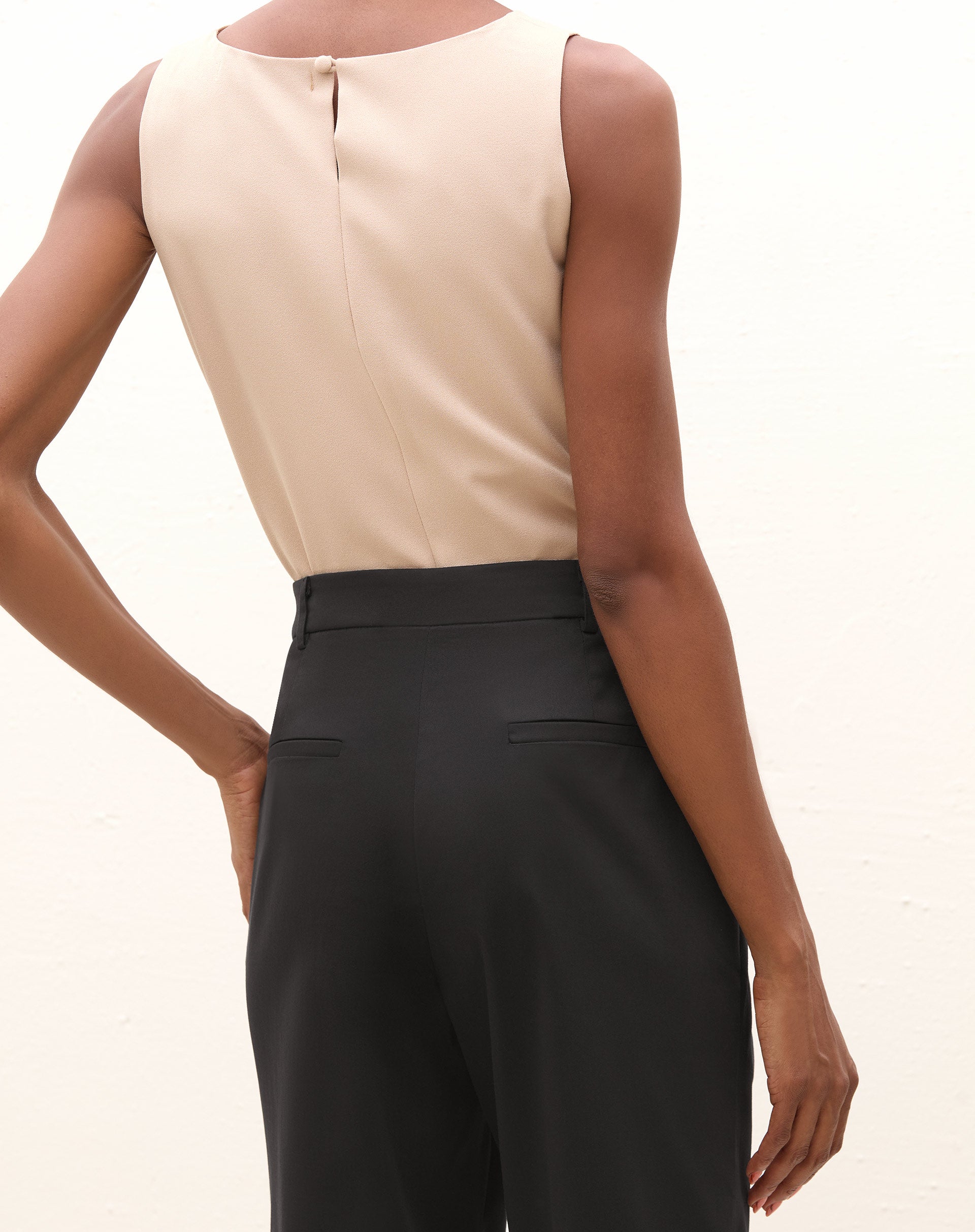 Vista traseira detalhada da calça de alfaiataria baggy preta com pregas.