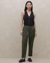 Modelo vestindo calça baggy verde escuro com colete preto, vista frontal.