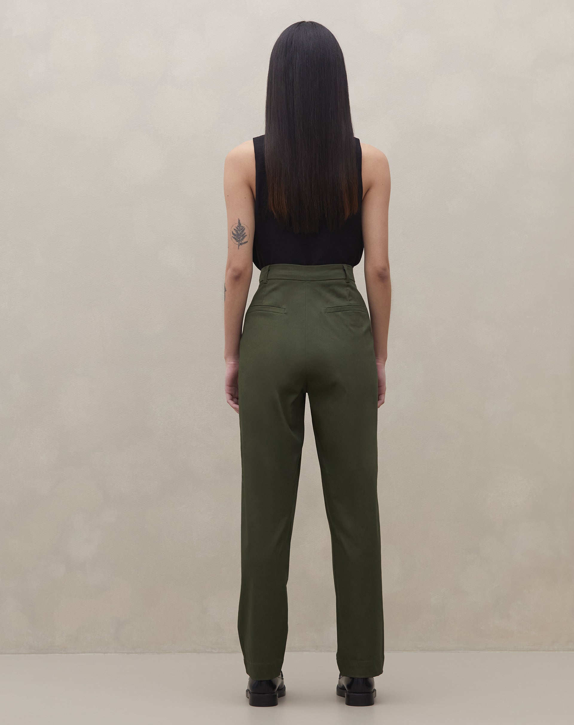 Modelo com calça baggy verde escuro e colete preto, pose casual.
