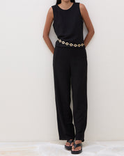 Modelo vestindo calça preta reta com cós elástico, combinada com blusa preta e sandália.