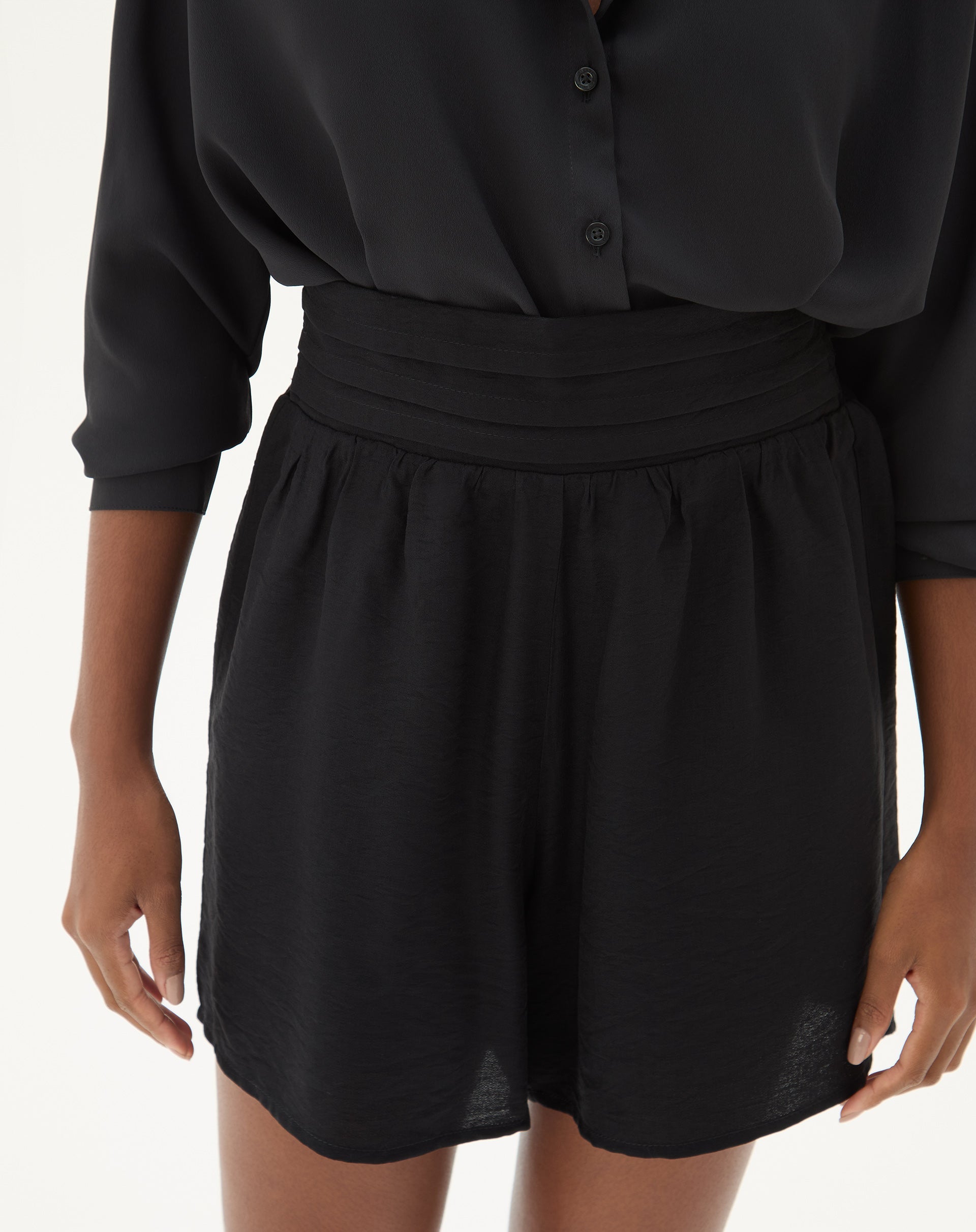 Close-up do cós alto e elástico do shorts preto.