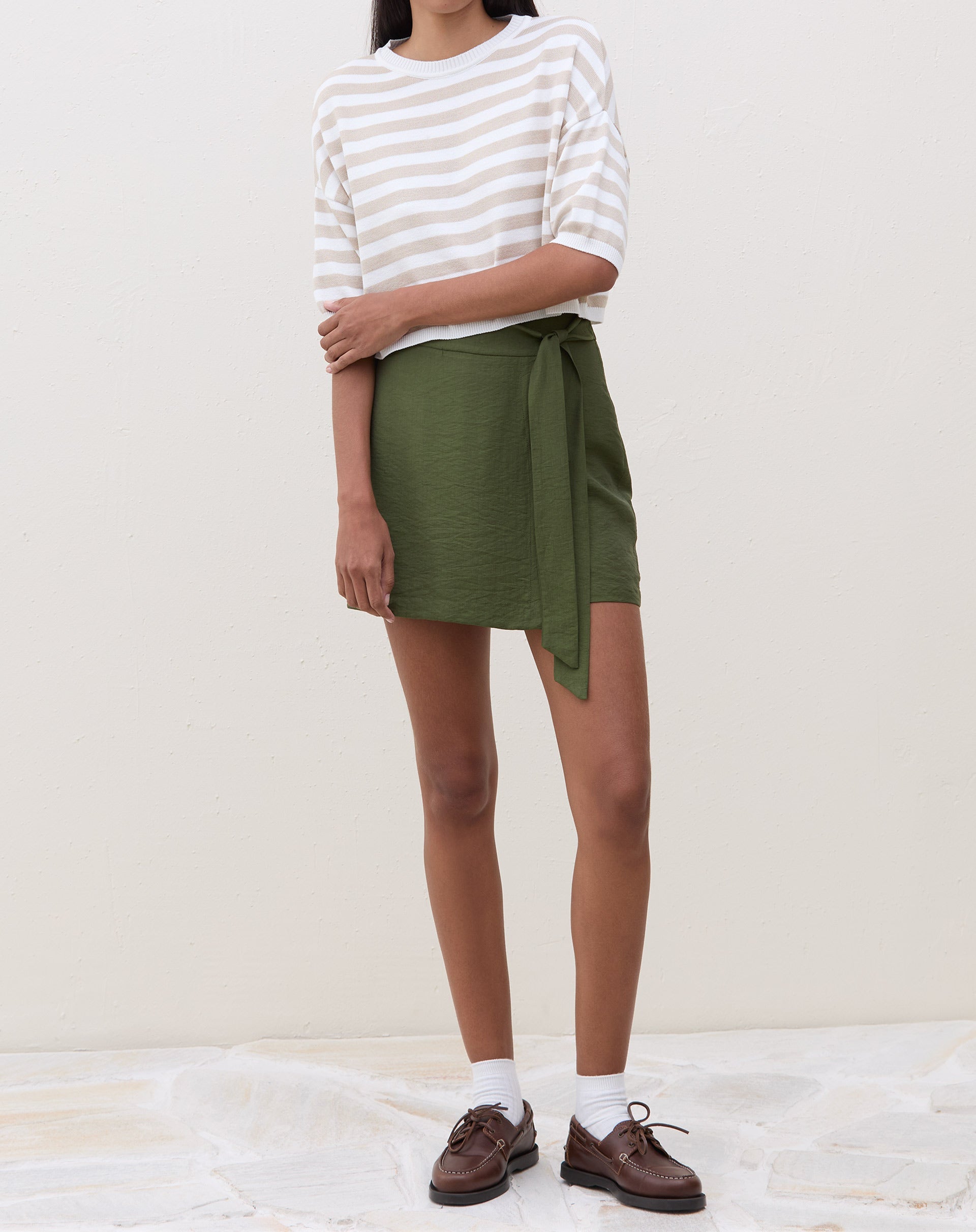 Vista frontal da saia curta transpassada verde militar com amarração.
