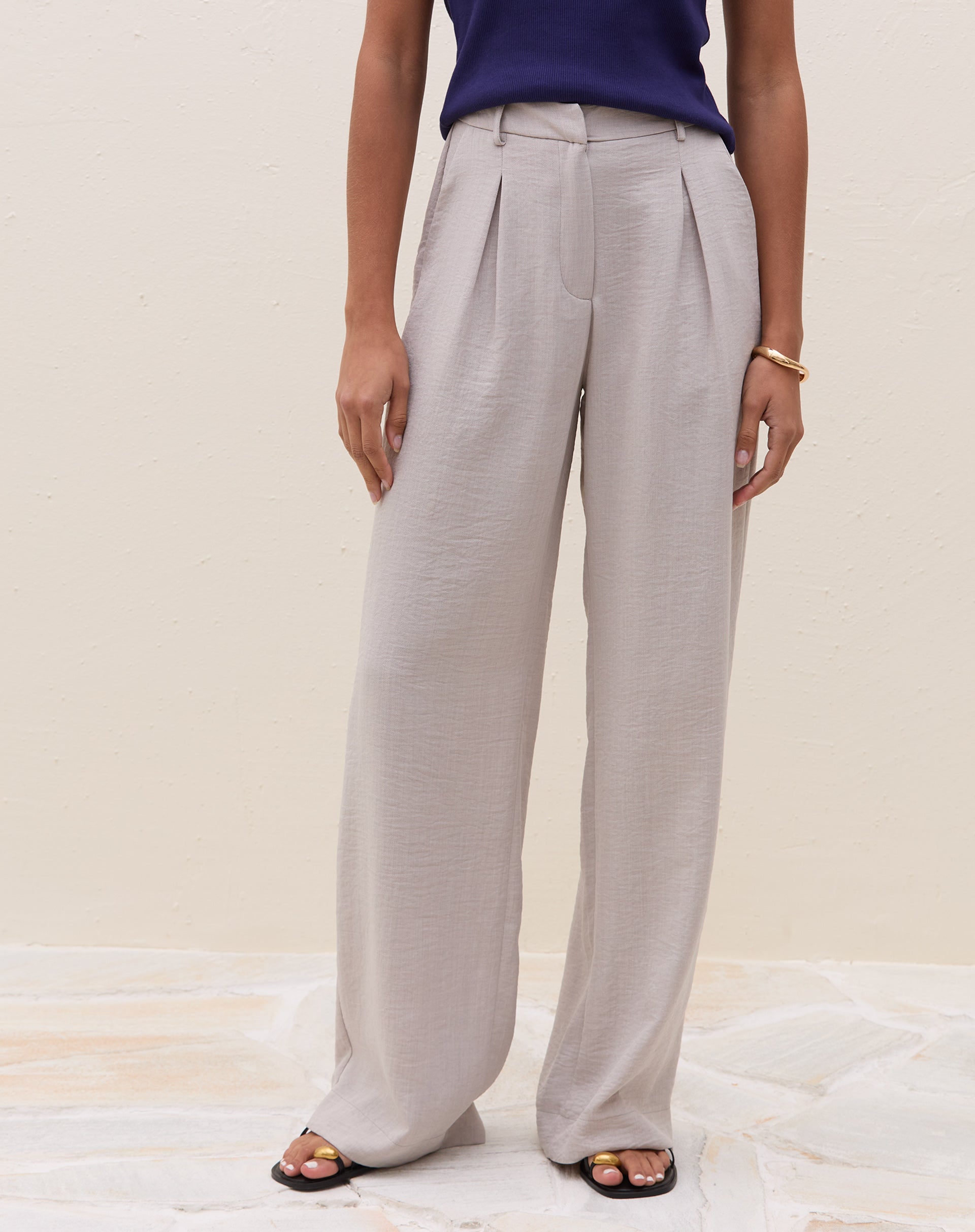 Vista frontal da calça cinza claro com cintura alta e pregas.
